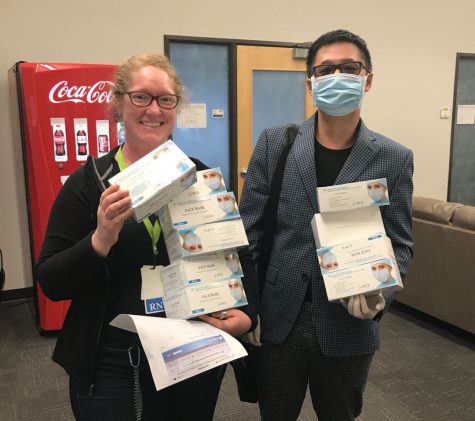 Liu poses with a smiling health worker, holding boxes of donated masks.