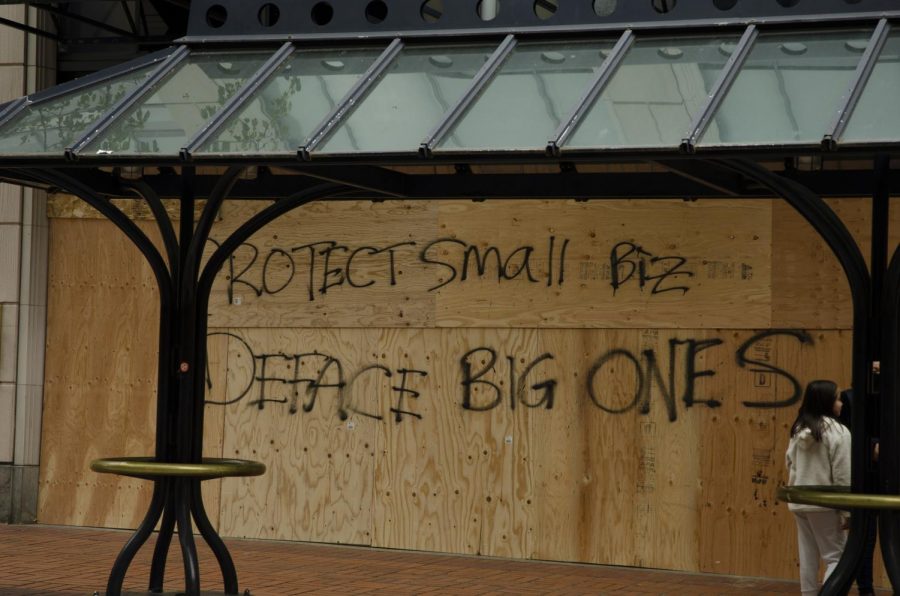 Graffiti in front of the boarded up Louis Vuitton building reads Protect small biz, Deface big one.